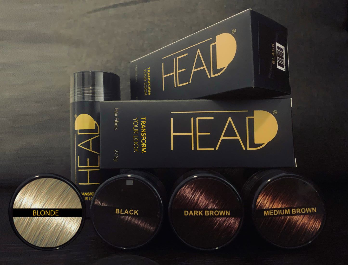 A variety of Headd Hair Fiber bottles in different colors, showcasing the product's range. Options include shades such as blonde, black, dark brown, and medium brown, providing versatile choices for users to match their hair colour.